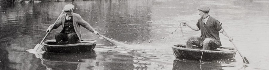 Fishermen netting in coracles on river.